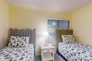 a bedroom with two beds and a table with a lamp at ABPAB167 Blue Haven Beach Retreat in Atlantic Beach +30 photos