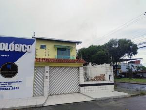 a small yellow house with a sign in front of it at Edícula Planalto in Manaus