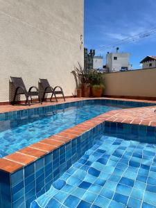 a swimming pool with two chairs next to a building at Estalagem Portucale in Águas de Lindoia