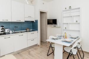 a kitchen with white cabinets and a white table and chairs at Cala Lupo Relax Veranda e BBQ nel verde in Stintino