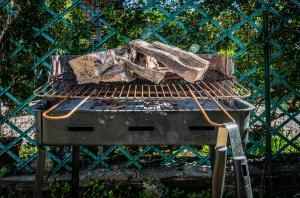 a grill with two pieces of wood on it at Cala Lupo Relax Veranda e BBQ nel verde in Stintino