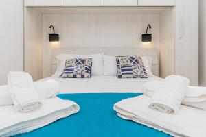 a bedroom with a white bed with towels on it at Cala Lupo Relax Veranda e BBQ nel verde in Stintino
