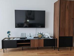 a black entertainment center with a tv on a wall at Sunny apartment208 in Dunajská Streda +25 photos