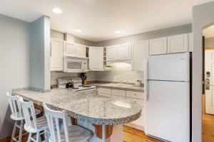 a kitchen with white cabinets and a white refrigerator at Cozy Studio Cottage on the River in Bend