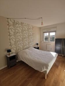 a bedroom with a bed and a wall at La coccinelle in Gujan-Mestras