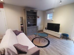 a living room with a white couch and a tv at La coccinelle in Gujan-Mestras