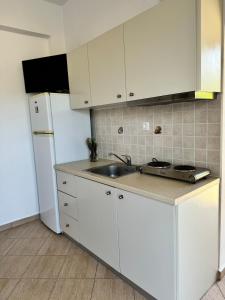 a kitchen with white cabinets and a sink and a refrigerator at Limnes Seaside Studio in Ligaridia