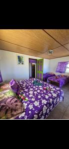 a bedroom with a bed with a purple comforter at Pension Tipapa in Tikehau