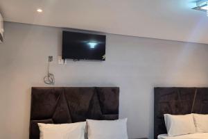 a flat screen tv on a wall above a bed at Ijumba Signature Hotel in Bellville
