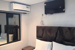 a bedroom with a couch and a tv on the wall at Ijumba Signature Hotel in Bellville