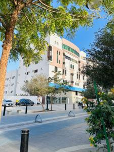 a large building on a city street with trees at Quba Suites نزل قباء in Medina