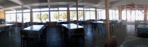 a dining room with tables and chairs and windows at To Akrogiali in Fánai