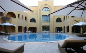 a large swimming pool in a building with umbrellas at Ksar El Jerid in Tozeur +10 photos