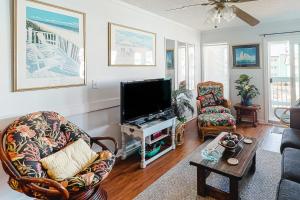 a living room with a flat screen tv and chairs at ABSS102 Seaspray 224 in Atlantic Beach
