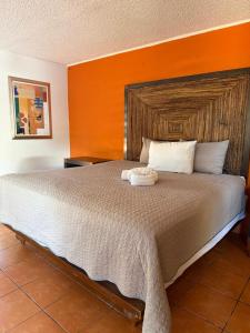 a bedroom with a large bed with an orange wall at Hacienda Rosarito in Rosarito Beach