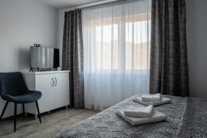 a bedroom with a bed and a chair and a window at Casa Puiu in Câmpulung Moldovenesc