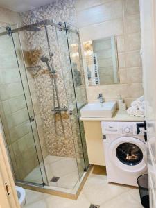 a bathroom with a shower and a washing machine at Holidays inkutaisi in Tsqnetʼi