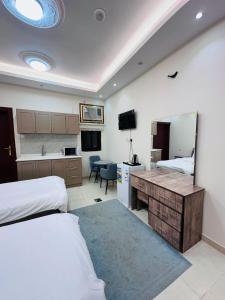 a bedroom with two beds and a desk and a kitchen at Quba Suites نزل قباء in Medina