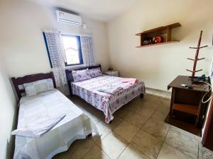 a bedroom with two beds and a table in it at Recanto the beach pousada in Iguape