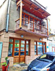 a house with a balcony and a car parked in front of it at Diuma 5 Guest house in Tbilisi City