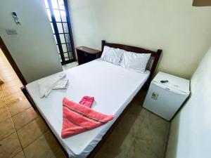 a white bed with a red towel on it at Recanto the beach pousada in Iguape