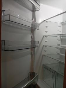 an empty refrigerator with its door open and a glass shelf at Balerna Swiss Apartment by RentuGoo Travel in Balerna +23 photos