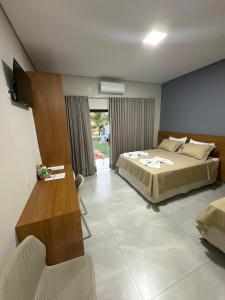 a bedroom with a bed and a desk and a television at Hotel Castelo do Lago in Fama