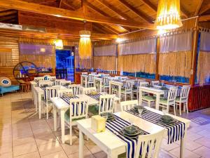 a dining room with white tables and white chairs at arzum bungalovs in Kumluca