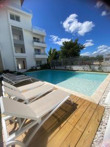 a swimming pool with lounge chairs next to a building at Apartamento Vacacional Coral Azul - SBH in Bayahibe