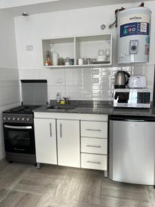 a kitchen with white cabinets and black appliances at Depto temporal in Morón