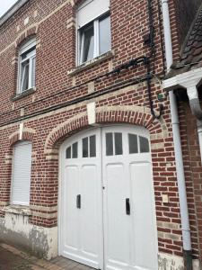 two white garage doors on a brick building at Esprit Gare in Haubourdin
