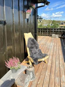 a stuffed animal sitting on a wooden chair on a deck at Mountain Cabin With Jacuzzi In Gautefall in Drangedal