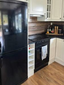 a black refrigerator in a kitchen with white cabinets at Mountain Cabin With Jacuzzi In Gautefall in Drangedal