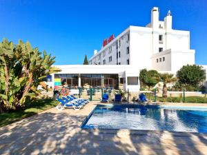 a hotel with a swimming pool in front of a building at Hotel ibis Faro Algarve in Faro