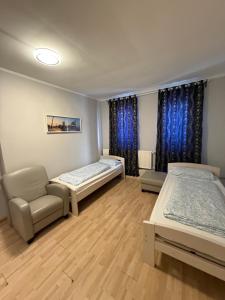 two beds and a chair in a room with blue curtains at Rest Best L97 in Hamburg