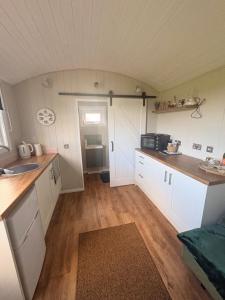 a kitchen with white cabinets and a counter top at Whitethorn Shepherds Hut in Bellaghy