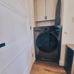 a black washing machine in a kitchen next to a door at Modern Nordic Cabin 2 Hot Tub & Views in East LaHave