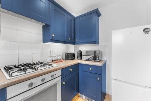 a kitchen with blue cabinets and a stove top oven at HomeBase Midlands Contractors Relocation Parking in Walsall
