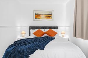 a bedroom with a white bed with two orange pillows at HomeBase Midlands Contractors Relocation Parking in Walsall