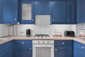 a kitchen with blue cabinets and a stove top oven at HomeBase Midlands Contractors Relocation Parking in Walsall +49 photos