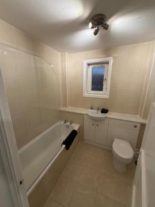 a bathroom with a tub and a toilet and a sink at Spacious 2 bed apartment with private parking space in Edinburgh