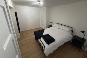 a bedroom with a bed with white sheets and black pillows at Spacious 2 bed apartment with private parking space in Edinburgh