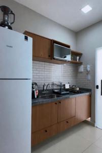 a kitchen with a white refrigerator and wooden cabinets at Villa Safira Residence in Caxias das Aldeias Altas +1 photo