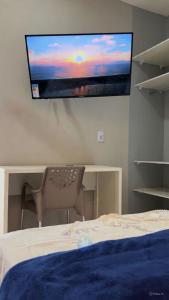 a flat screen tv hanging on a wall above a bed at Villa Safira Residence in Caxias das Aldeias Altas