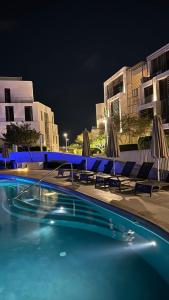 a swimming pool with chairs and umbrellas at night at Ayla Oasis Luxury Chalets - Azure & Golf in Aqaba