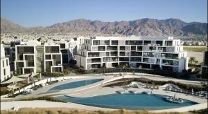 arial view of a hotel with a swimming pool and buildings at Ayla Oasis Luxury Chalets - Azure & Golf in Aqaba