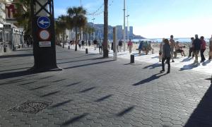 a group of people walking on a sidewalk near the beach at Apartamento REX in Benidorm