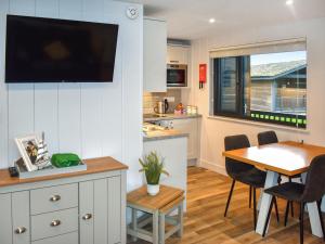 a kitchen and dining room with a table and a tv on the wall at Lodge 6- Uk51084 in Lyme Regis