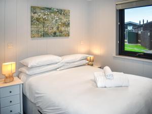 a bedroom with a bed with white sheets and a window at Lodge 6- Uk51084 in Lyme Regis