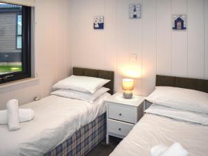 two beds in a small room with a lamp on a night stand at Lodge 6- Uk51084 in Lyme Regis +2 photos